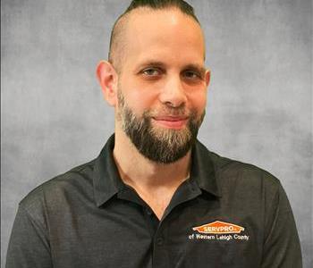 A man wearing a servpro polo in front of a grey screen and servpro logos