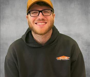 A man wearing a servpro hoodie in front of a grey screen and servpro logos