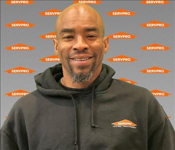 A servpro employee wearing a servpro hoodie in front of a gray backdrop
