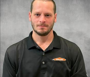 A servpro employee wearing a servpro polo in front of a gray backdrop