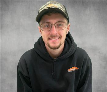 A man wearing a servpro hoodie in front of a grey screen and servpro logos